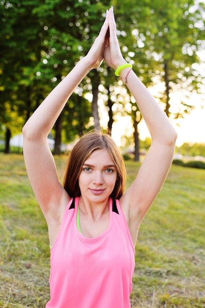 Retrato de una niña que hace yoga en la hierba verde