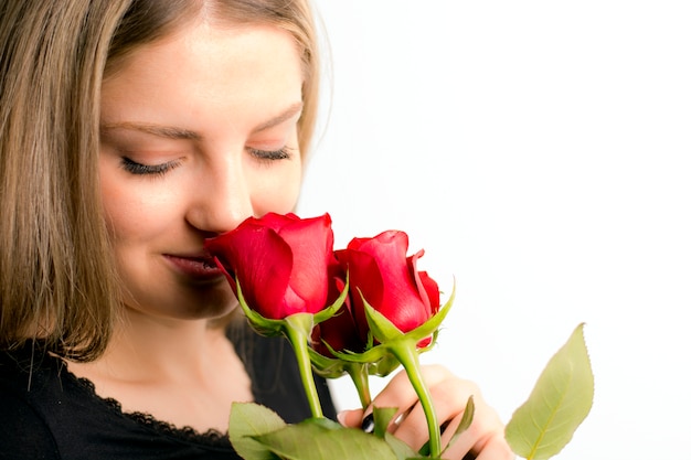 Foto retrato de una niña que huele flores rosas rojas