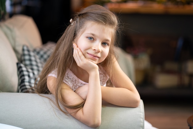 Retrato de una niña que yace en el sofá, apoyada en su brazo