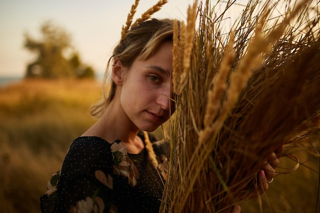 retrato de una niña con un ramo de flores silvestres niña camina por el campo al atardecer