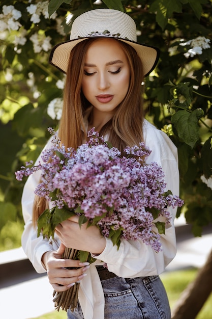 Retrato de una niña con un ramo de lilas. maquillaje de verano paseo de verano en el parque