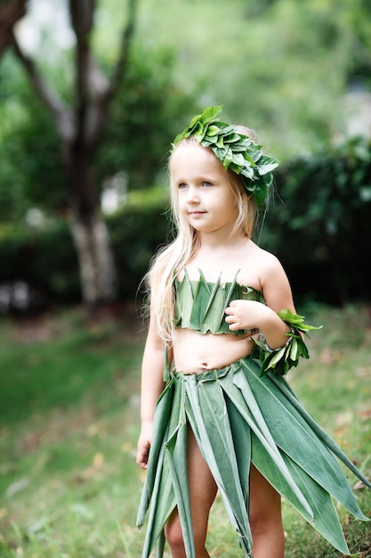 Retrato de niña rubia linda en traje de carnaval de hierba verde al aire libre