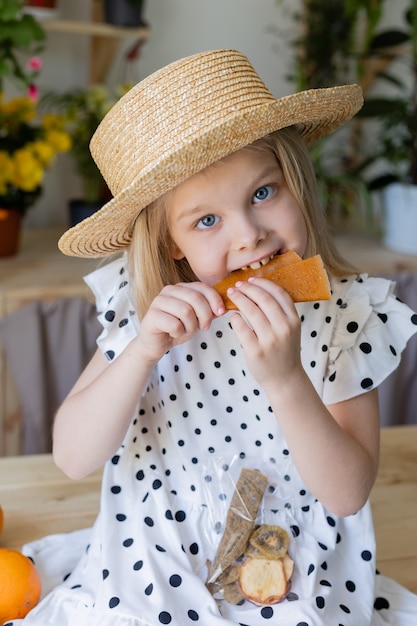 Retrato de una niña rubia sostiene una naranja pelada en sus manos y se la come en el estilo de vida