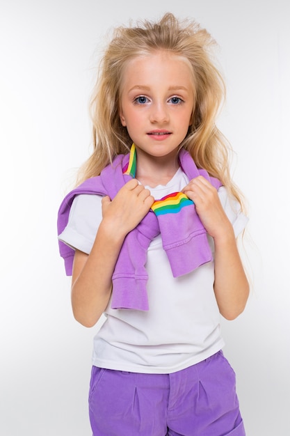 Retrato de una niña rubia con un suéter sobre sus hombros sobre un blanco