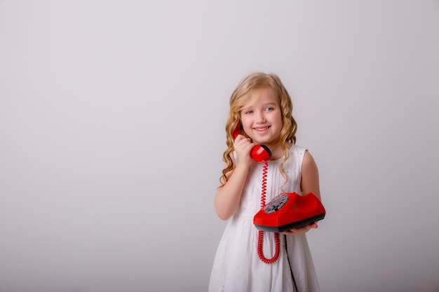 Retrato de una niña rubia con un teléfono viejo en sus manos