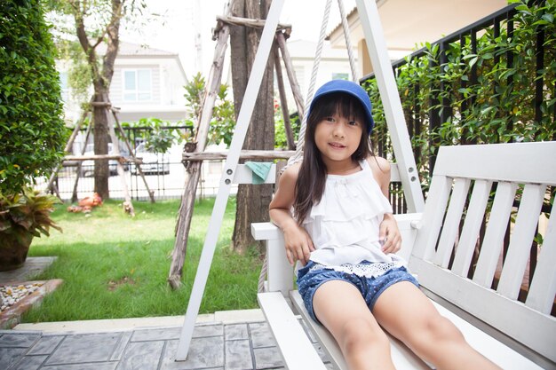 Retrato de una niña sentada en un columpio en el patio