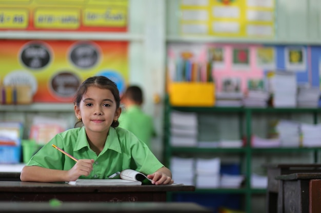 Foto retrato de una niña sentada en una mesa en el aula