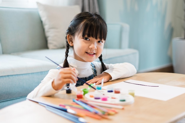 Retrato de una niña sentada y pintando en casa