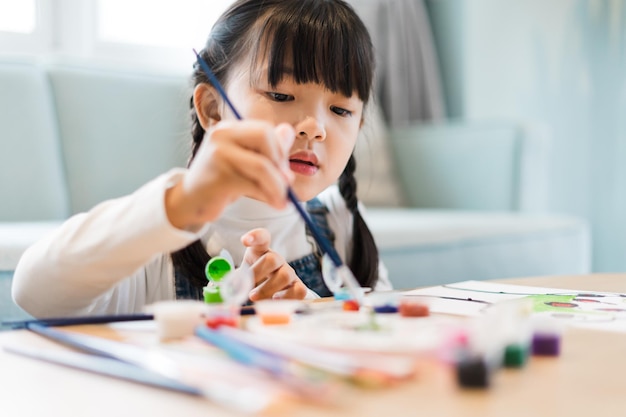 Retrato de una niña sentada y pintando en casa