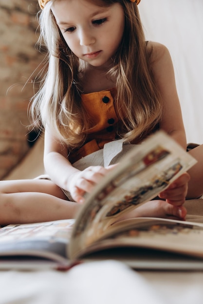 Retrato de una niña sentada en el suelo leyendo literatura infantil