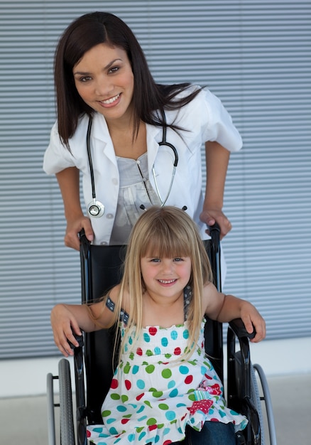 Retrato de una niña en una silla de ruedas y un joven médico