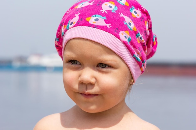 Retrato de niña con sombrero en la playa de verano mirando a un lado