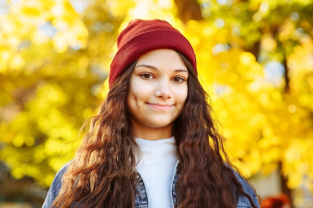 Retrato de una niña con sombrero rojo en otoño en el parque closeup