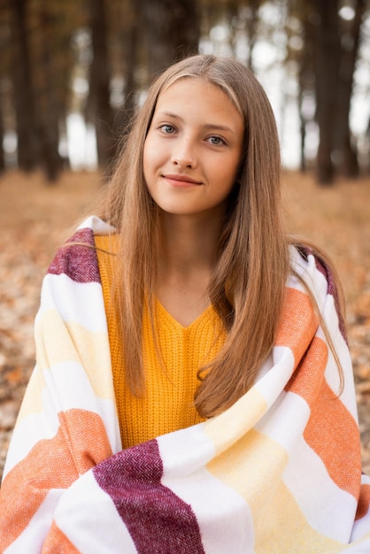 Retrato de una niña soñadora sonriente en el parque de otoño mirando a la cámara