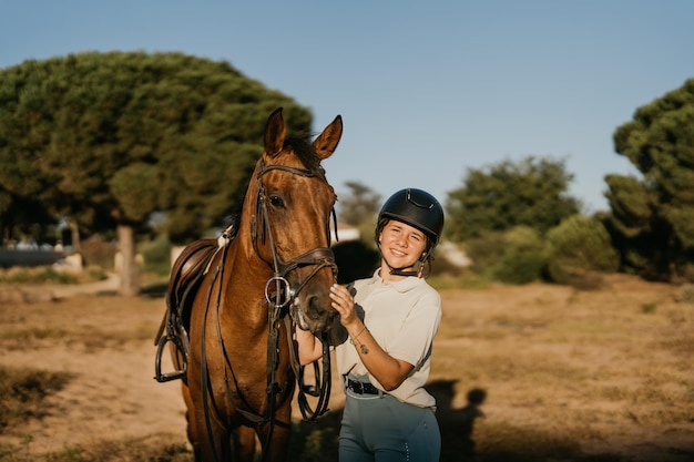 Retrato de una niña sonriente de 17 años sosteniendo su caballo por la cabeza