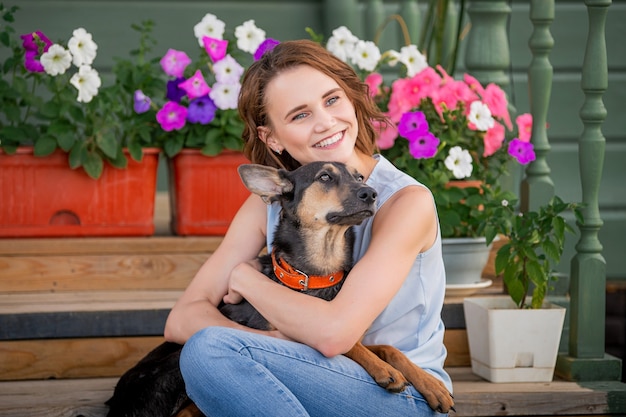 Retrato de una niña sonriente abrazando a un gran cachorro gracioso