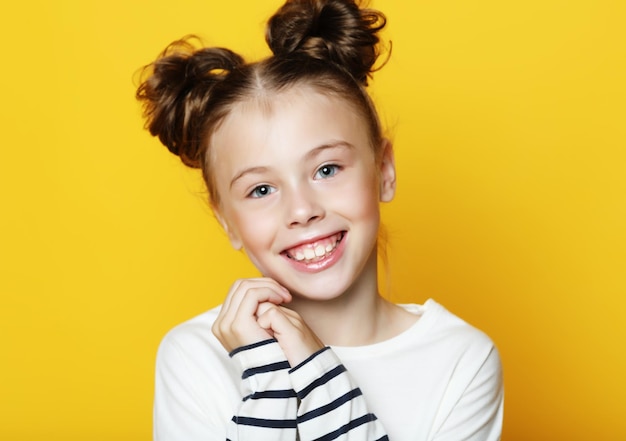 Retrato de niña sonriente alegre sobre fondo amarillo