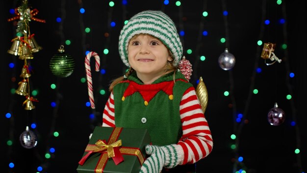 Foto retrato de una niña sonriente en un árbol de navidad iluminado durante el invierno