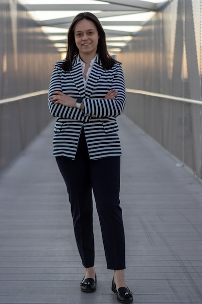 Retrato de niña sonriente con los brazos cruzados sobre un puente en la ciudad Mujer joven sonriente de pie con los brazos cruzados sobre un puente