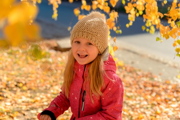 Retrato de niña sonriente caminando en el parque de otoño en scooter