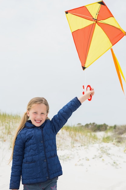 Retrato de una niña sonriente con cometa en la playa