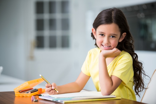 Retrato de niña sonriente estudiando en el escritorio