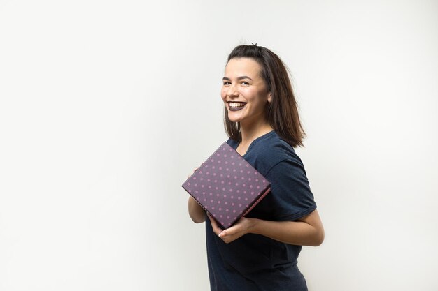 Retrato de una niña sonriente feliz abriendo una caja de regalo aislado sobre fondo blanco.