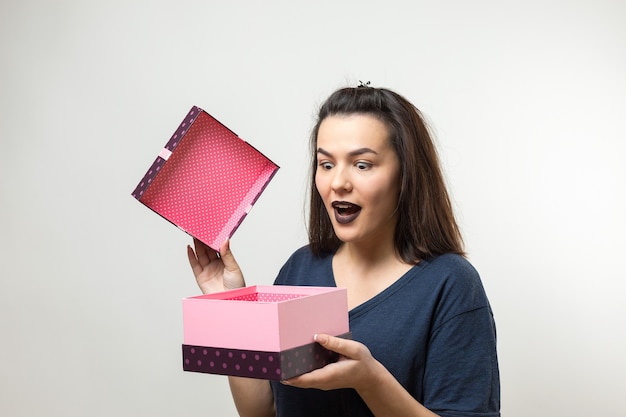 Retrato de una niña sonriente feliz abriendo una caja de regalo aislado sobre fondo blanco.