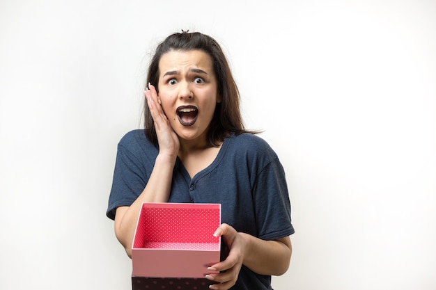 Retrato de una niña sonriente feliz abriendo una caja de regalo aislado sobre fondo blanco.