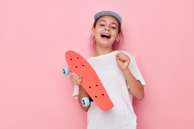 Retrato de niña sonriente feliz gorra en camiseta blanca monopatín infancia inalterada