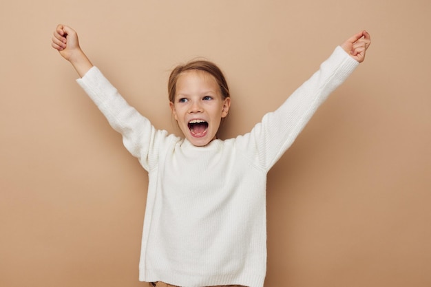 Retrato de niña sonriente feliz en suéter blanco posando gestos de mano infancia inalterada