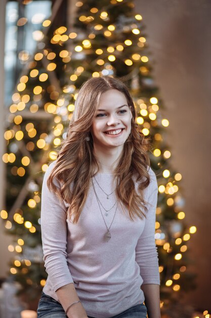 Retrato de una niña sonriente en el fondo de un árbol de año nuevo en Navidad