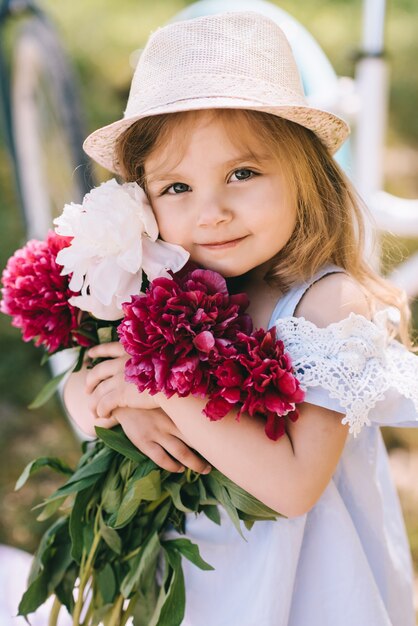 Retrato de una niña sonriente con gran ramo de flores