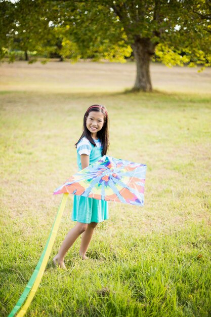 Retrato de niña sonriente jugando con la cometa en el parque