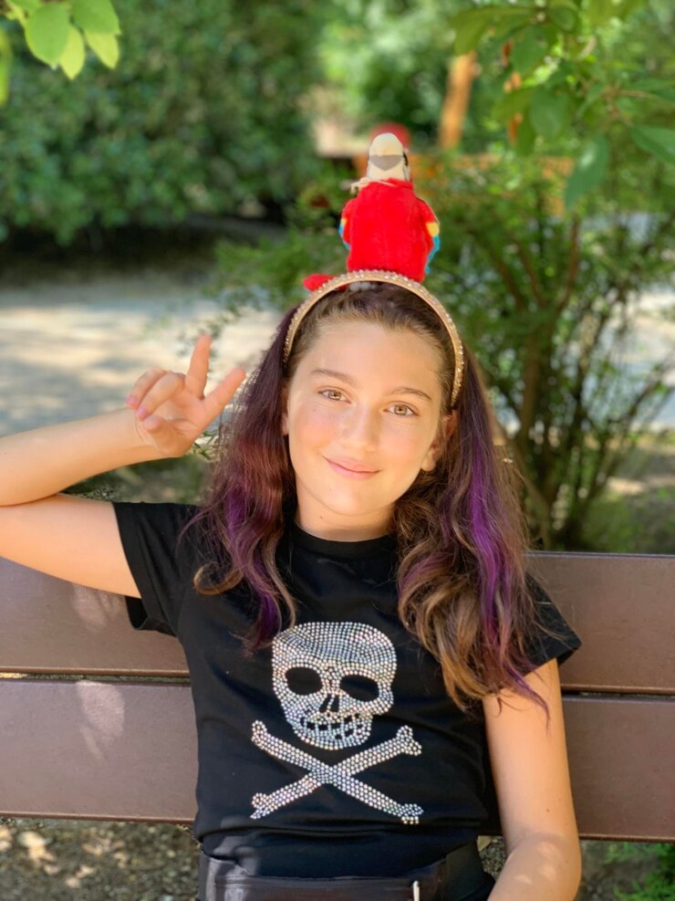 Foto retrato de una niña sonriente mostrando un signo de paz mientras está sentada en un banco