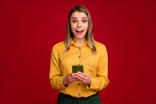 Retrato de niña sorprendida con conexión rápida de la aplicación de venta celular aislada sobre fondo de color rojo