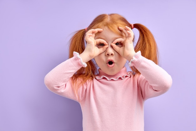 Retrato de niña sorprendida linda que se encuentran aisladas en púrpura