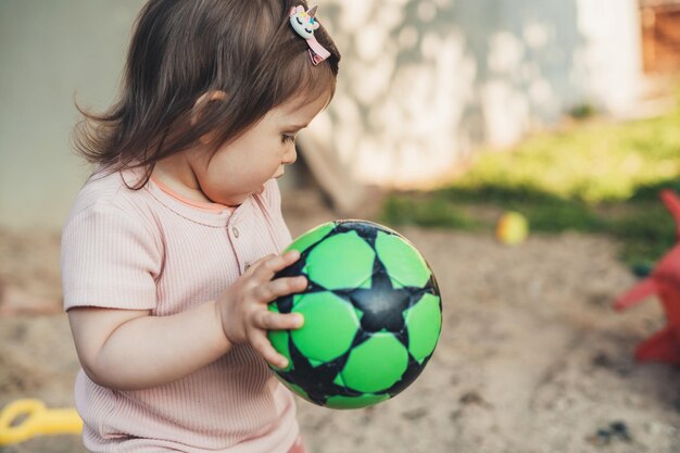 Retrato de niña sosteniendo un balón de fútbol de juguete y listo para lanzarlo Desarrollo del bebé Niño activo jugando al aire libre