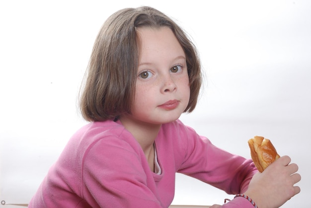Foto retrato de una niña sosteniendo comida contra un fondo blanco