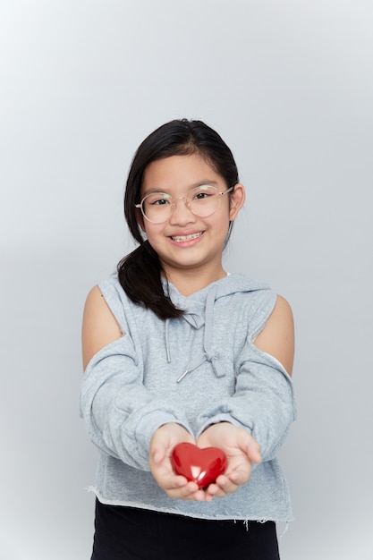 Retrato de una niña sosteniendo una forma de corazón rojo