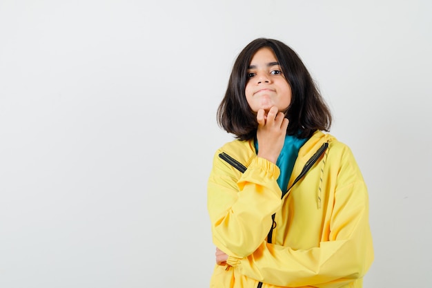 Retrato de niña sosteniendo la mano debajo de la barbilla en camisa, chaqueta y mirando bonita vista frontal