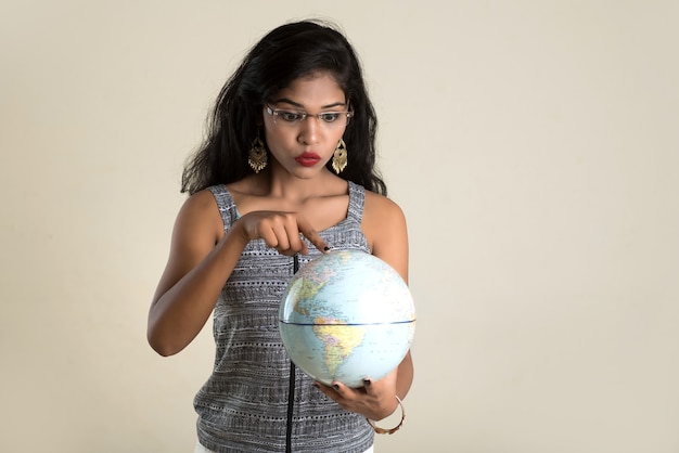 Retrato de niña sosteniendo y posando con un globo terráqueo.