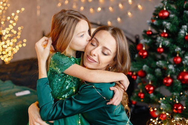 Retrato de una niña y su madre abrazándose en el ambiente navideño