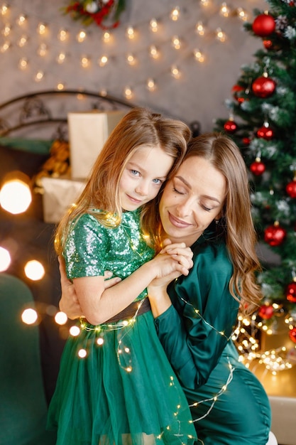 Retrato de una niña y su madre abrazándose en el ambiente navideño