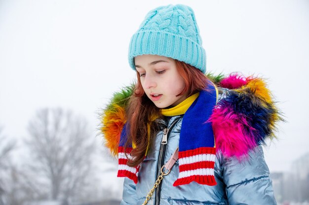 Retrato de niña en su ropa de abrigo. Adolescente con un sombrero azul en la nieve.