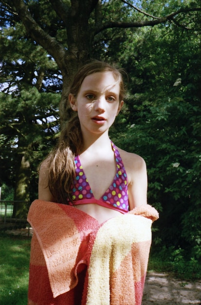 Foto retrato de una niña con una toalla mientras está de pie contra los árboles