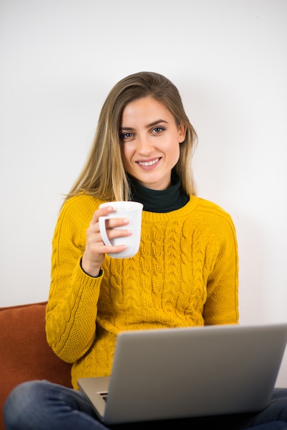 Retrato de una niña trabajando en casa. Sosteniendo una taza y mirando a la cámara.