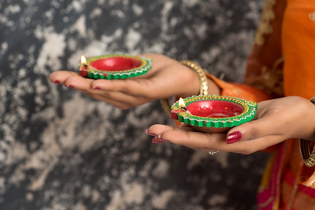 Retrato de una niña tradicional india sosteniendo Diya, niña celebrando Diwali o Deepavali con lámpara de aceite durante el festival de la luz.