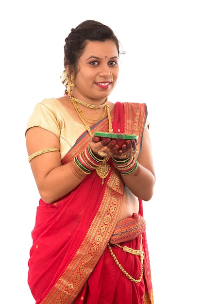 Retrato de una niña tradicional india sosteniendo pooja thali con diya durante el festival de la luz en blanco