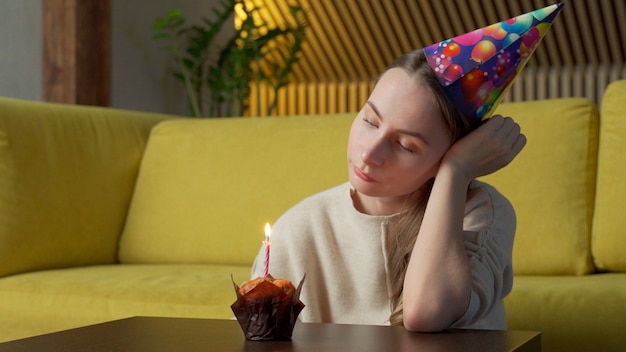 Retrato de una niña triste con un trozo de tarta con una vela, la niña apaga la vela